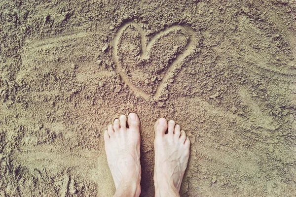 heart shape on the sand with feet, love for beach holidays