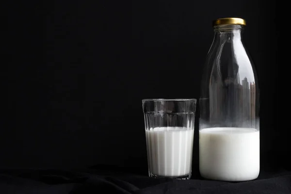 Botella de leche y un vaso para el desayuno sobre fondo negro — Foto de Stock