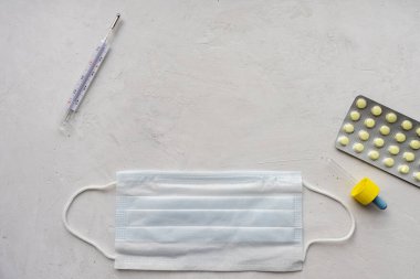 Haplar, termometre ve gri sırtında koruyucu tıbbi maske.