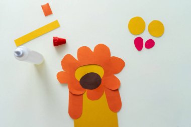 Bir çocuk kağıttan ve kartondan aslan yapar. Master sınıfı, DIY, Afrika hayvanları, sarı renk. İzolasyon üzerine ev yapımı çalışma.