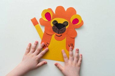Bir çocuk kağıttan ve kartondan aslan yapar. Master sınıfı, DIY, Afrika hayvanları, sarı renk. İzolasyon üzerine ev yapımı çalışma.