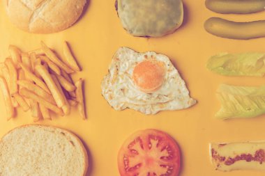 Sarı arkaplanda hamburger yapmak için gerekli malzemeler