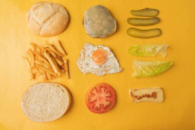 Sarı arkaplanda hamburger yapmak için gerekli malzemeler