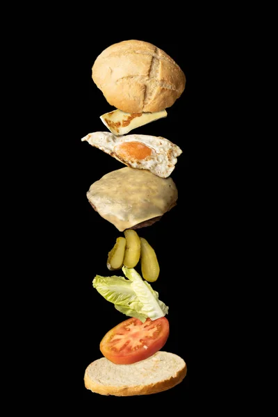 Delicioso Hambúrguer Com Ingredientes Levitando Fundo Preto — Fotografia de Stock