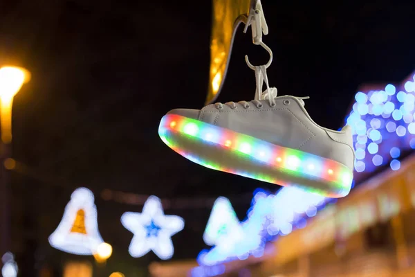 Sportive shoe hanging on blurred background of lights in dark — Stock Photo, Image