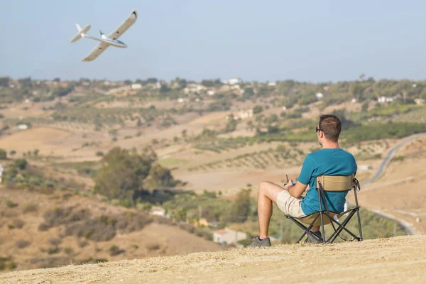 Man with remote control plane flying in air — Stock Photo, Image