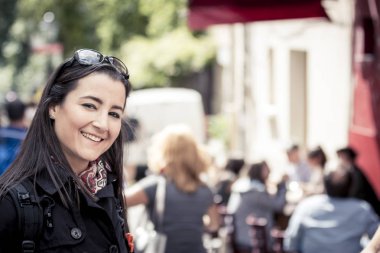 Yoğun bir cadde kameraya gülümseyen genç casual kadın