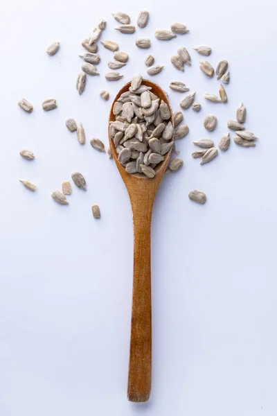 Spoon full of sunflower grains on white background — Stock Photo, Image