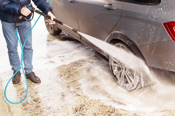 Man washing car. Cleaning car using high pressure water
