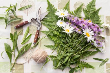 Çiçekçi işyeri. Çiçekler ve masa üzerinde papatyalar olan bir buket yapmak için aletler.