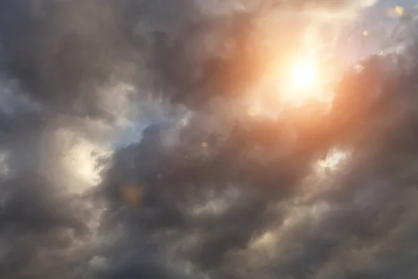 Epic dramatic storm dark grey clouds, sky with orange sun and sunlight, heaven
