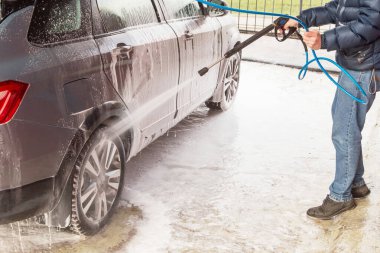 Adam araba yıkıyor. Yüksek basınçlı su ve köpük kullanarak temizleme aracı