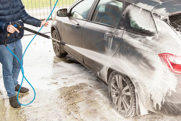 Man washing car. Cleaning car using high pressure water and foam