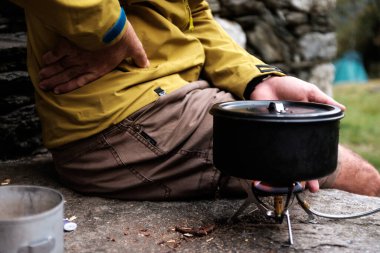 Kamp sobasının yanında ellerini ısıtan bir adamın yan görüntüsü. 