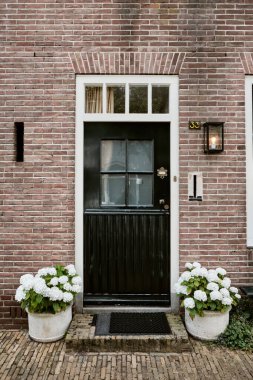 Naarden, Hollanda - 7 Temmuz 2019: Ortaçağ kalesindeki tuğla duvardaki geleneksel siyah kapı