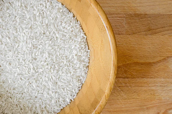 Ahşap bir tezgah ahşap bir kasede beyaz pirinç mükemmel