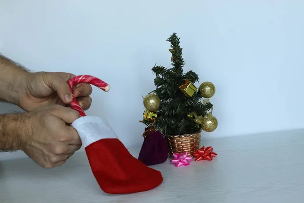 La mano del hombre pone una piruleta en un calcetín rojo de Año Nuevo. Decorado un — Foto de Stock