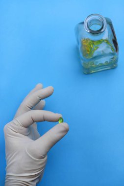 Beyaz eldivenli erkek doktorlar ellerinde balıklı bir kapsül tutuyorlar. 