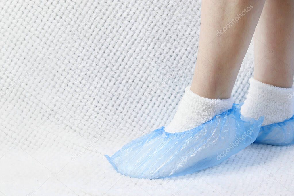 Blue shoe covers put on legs on a white background. Copy space - concept of cleanliness, health, disease prevention, security