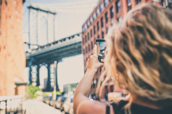 Woman photographing Manhattan Bridge during her vacation in New York