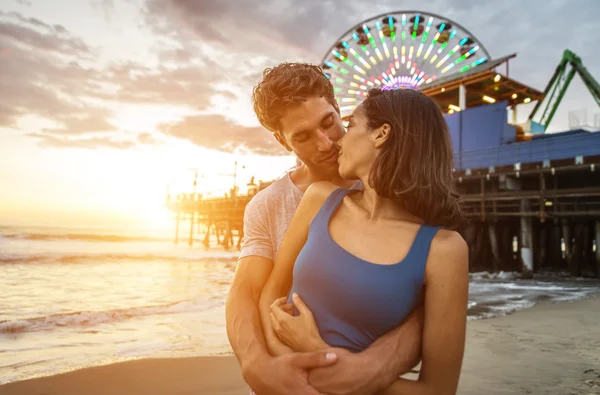 Par kyssar vid solnedgången på stranden — Stockfoto