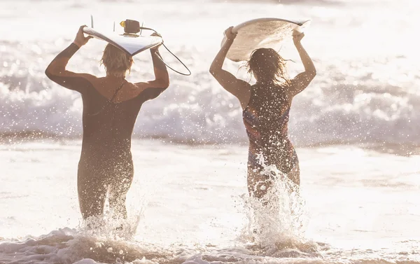 Surfisti che corrono in acqua con tavole — Foto Stock