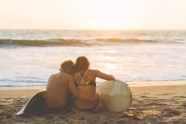 Pareja de surfistas sentados en la playa — Foto de Stock