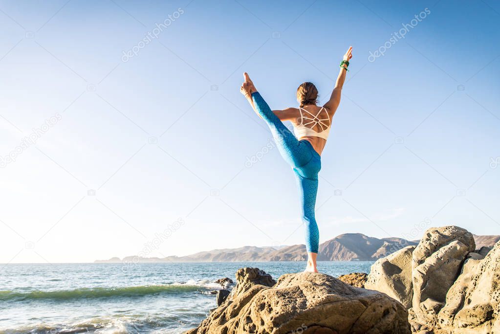 Woman practicing yoga on beach 