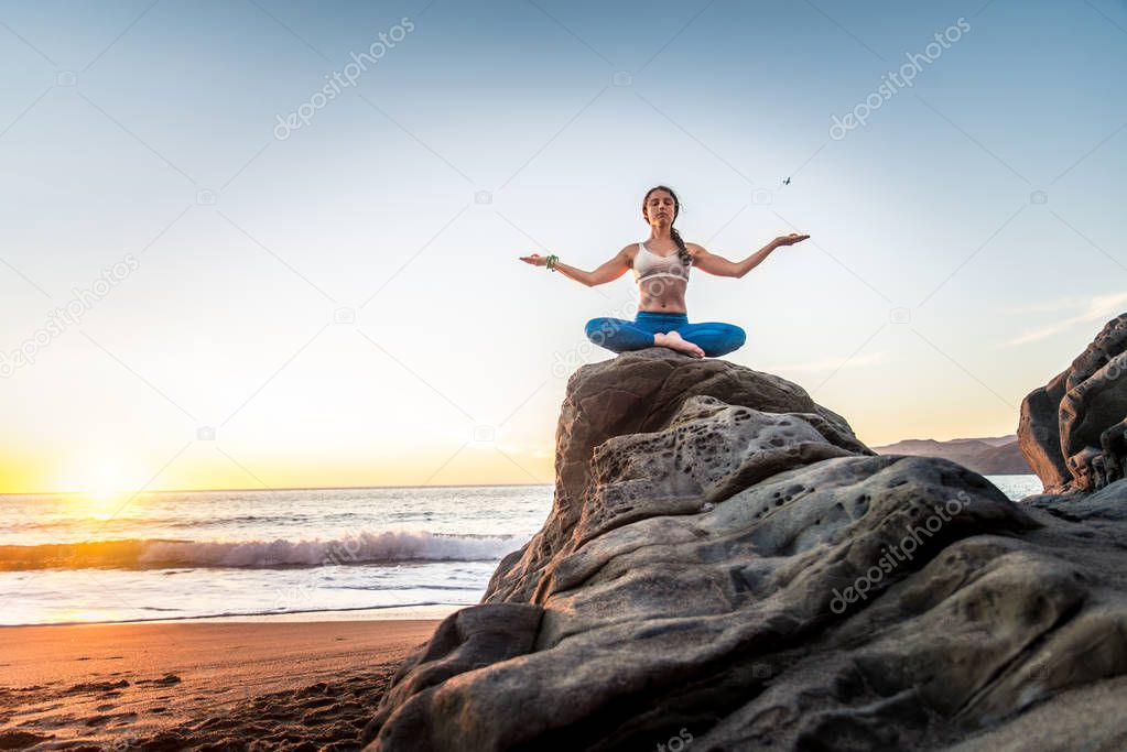 Woman practicing yoga on beach 