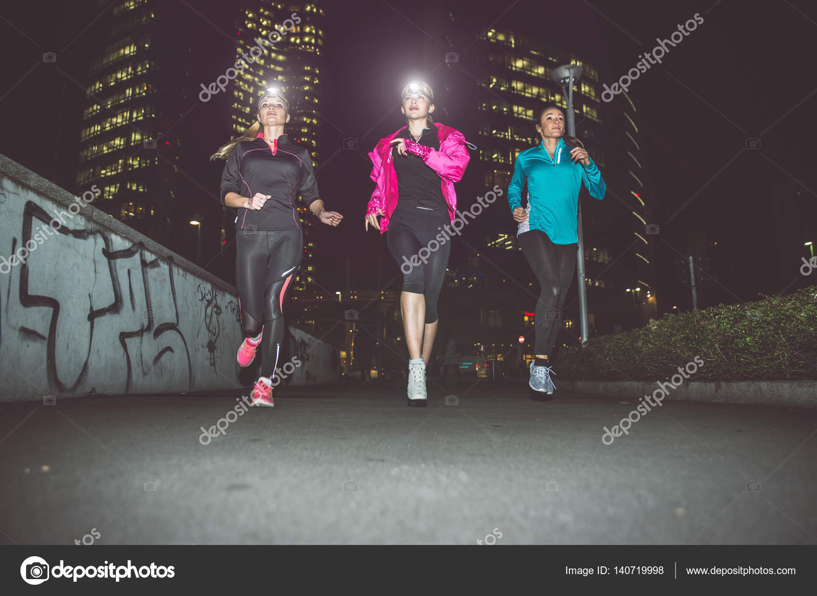Three women running in the night in the city center — Stock Photo