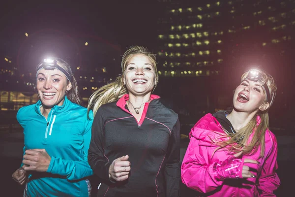 Three women running in the night in the city center — Stock Photo, Image