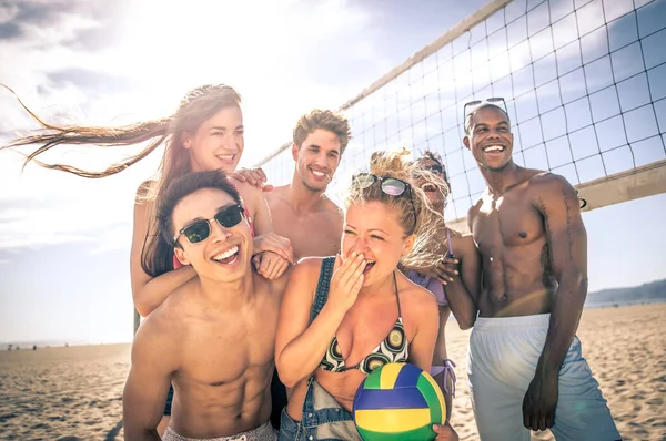 Grupo de amigos jogando vôlei de praia na praia e se divertindo — Fotografia de Stock