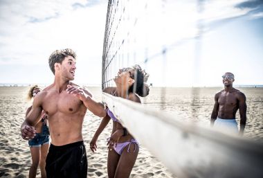 Plaj voleybolu oynarken arkadaşlar