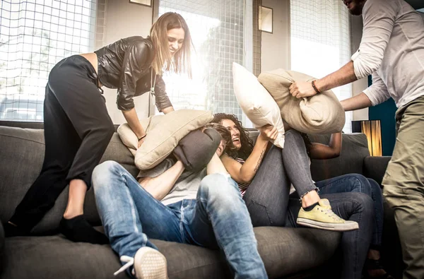 Amigos divirtiéndose en el sofá y haciendo pelea de almohadas —  Fotos de Stock