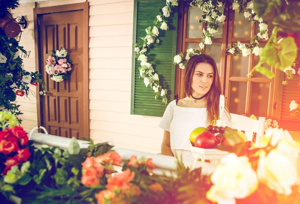 Wanita muda tinggal di depan rumah bunga yang indah — Stok Foto