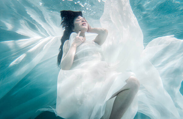 Beautiful woman swimming with fancy dress underwater