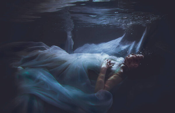 Beautiful woman swimming with fancy dress underwater