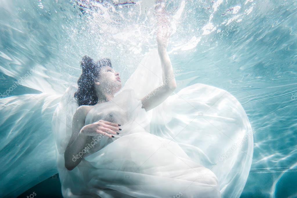 Beautiful woman swimming with fancy dress underwater