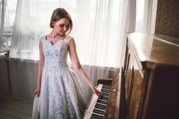 Beautiful woman with fancy elegant dress posing in the piano roo — Stock Photo, Image