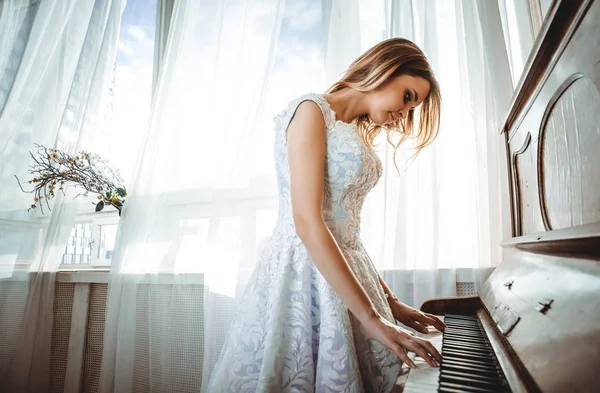 Krásná žena s ozdobný elegantní šaty pózuje v klavírní roo — Stock fotografie