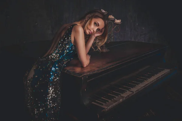 Όμορφη γυναίκα με φανταχτερά κομψό φόρεμα θέτοντας σε το πιάνο roo — Φωτογραφία Αρχείου