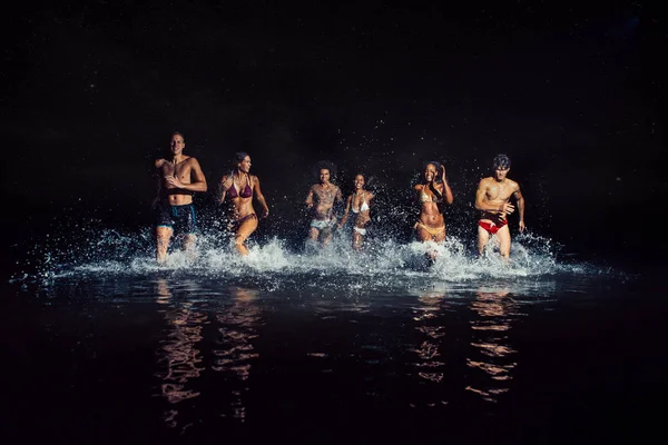 Grupo de amigos tomando un baño nocturno en el océano —  Fotos de Stock