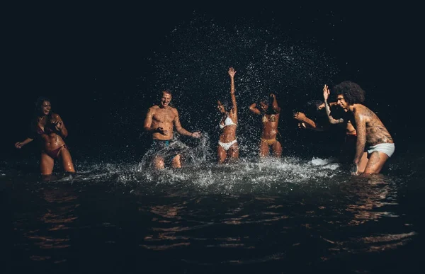Grupo de amigos tomando un baño nocturno en el océano — Foto de Stock
