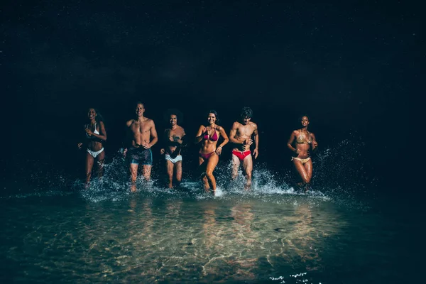 Grupo de amigos tomando un baño nocturno en el océano —  Fotos de Stock