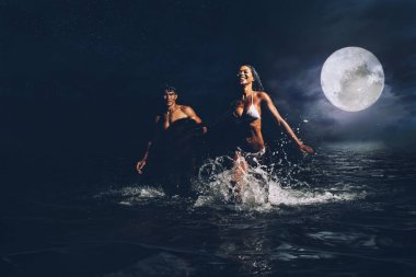 Okyanusta gece banyo sırasında çalışan genç Çift