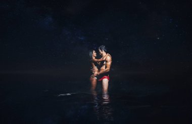 Genç çift okyanusta gece banyo sırasında öpüşme
