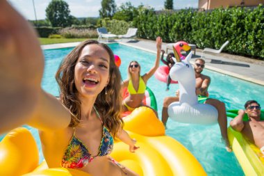 Arkadaşlar eğlenmeye bir yüzme havuzunda