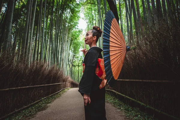 Beautiful japanese senior woman walking in the bamboo forest