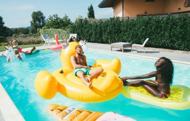 Bir grup arkadaş havuzda eğleniyor. 