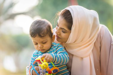 Arap anne ve küçük bebeği dışarıda oynuyorlar.